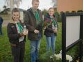 Harcerze stoją przed tablicą trzymając w rękach znicze i kwiaty