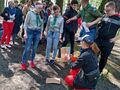Grupa uczniów wykonuje zadania gry terenowej. Słuchają wyjaśnień nauczyciela 