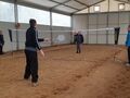 Chłopak i dziewczyna grają w badmintona, nauczyciel sędziuje, inna zawodniczka przygląda się