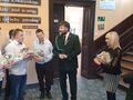 Uczniowie trzymają prezenty w rękach Pan Paweł Lisiak rozmawia z uczniami Pani Dyrektor stoi obok uczniów goście z PZŁ stoją z boku i przyglądają się