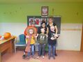 Trzy przebrane nauczycielki stoją wraz z trojgiem uczniów przed tablicą wszyscy uśmiechają się