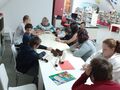 1. Uczniowie słuchający opowiadania siedzą przy stole w bibliotece
