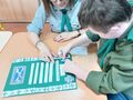 Druhna z druhem kończą tworzyć harcerskie pozdrowienia przylepiając na wielkiej zielonej kartce symbol lilijki
