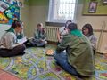 Harcerze siedzą w kole na podłodze przy świecach i śpiewają harcerskie piosenki