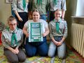 Harcerze wspólnie pozują do zdjęcia z kartką z pozdrowieniami dla innych drużyn