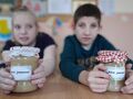 8. Dziewczynka i chłopiec prezentują swoje dżemy w ozdobionych słoiczkach