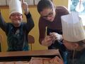 2 Dzieci z nauczycielem rozkładają składniki na pizzęjpg