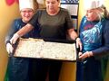 5 Pani trzyma blachę z gotową pizzą do piekarnika obok niej stoi dwóch chłopców