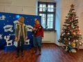 uczeń przebrany za pasterza uczennica za staruszkę stoją na tle wystroju świątecznego i choinki