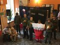 Harcerze stoją w holu ośrodka trzymają flagę Polski i śpiewają Hymn Państwowy