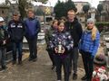 Harcerze znajdują się na cmentarzu jeden z nich trzyma znicz w tle widać nagrobki drzewa i domy