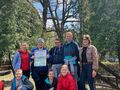 Grupa uczniów stoi na dworze wtle widać park. Jeden uczeń trzyma w ręce plakat 