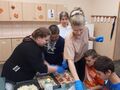 6. Uczniowie rozkładający składniki na pizzy z pomocą nauczycielki