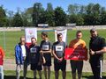 9. Uczniowie stoją na torze kolarskim. Obok nauczyciel i nauzycielka. Uczeń trzyma tablicę z napisem SOSW Konarzew 