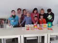 1.Uczniowie z nauczycielami w bibliotece pozują do zdjęcia na stoliku leżą wykonane kartki wielkanocne