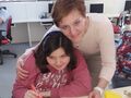 5. Uczennica z pomocą nauczyciela wykleja kurczaka z papieru na kartce wielkanocnej