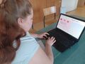 Uczennica siedzi przy stoliku i wykonuje zadanie konkursowe na komputerze 