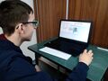 Uczeń siedzi przy stoliku i wykonuje zadanie konkursowe na komputerze 