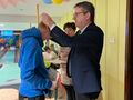 Uczeń pochyla głowę do przodu. Przed nim Burmistrz Zdun.Zawiesza uczniowi medal na szyi. Obok kobieta trzyma w ręce dyplomy