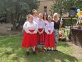 8. Przed sceną dziewczyny w czerwonych spódnicach obok nauczycielki 