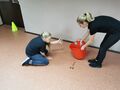2 Chłopiec zbiera przedmioty leżące na ziemi i wrzuca je do pudełka