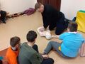 2.ratownik udziela instruktarzu prawidłowej resuscytacji na fantomie a grupa uczniów przygląda się