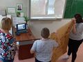 6 Uczniowie stoją i trzymają plakat pokazują go do kamery w laptopie