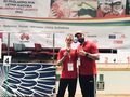 Srebrny medalista pozuje wraz z trenerem do zdjęcia na tle olimpijskiego podium