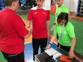 Zawodnicy przy stoliku sędziowskim gratulują sobie występu