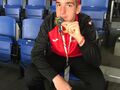 Zdobywca srebrnego medalu w grze w bocce prezentuje srebrny medal siedząc na trybunach