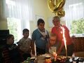 2 Chłopcy razem z opiekunką stoją przy stole na którym jest tort i słodycze a w tle balony 