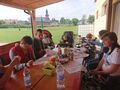 Piknik Chłopcy wraz z opiekunami siedzą na dworze przy dużym drewnianym stole na którym rozłożone są różne pyszne przekąski i sokiJPG