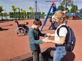 Plac zabaw na Błoniach w Krotoszynie Chłopiec asekurowany przez opiekuna za ręce skacze na mini trampoliniejpeg