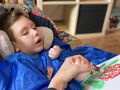Uczeń siedzi w siedzisku z granulatu i trzymamy przez nauczyciela za dłoń maluje kwiat na kolor czerwonyjpg