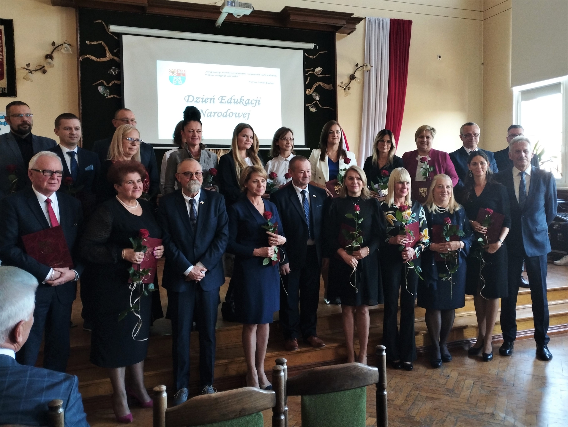 Dyrektorzy i nauczyciele wraz ze Starostą Krotoszyńskim, Wicestarostą Krotoszyńskim, Naczelnikiem Wydziału Edukacji, Kultury i Sportu, Przewodniczącym Rady Powiatu, Zastępcą naczelnika Wydziału Edukacji, Kultury i Sportu stoją na scenie w auli I Liceum Ogólnokształcącego w Krotoszynie