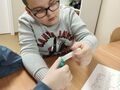 3. Wsypywanie sody do balona chłopiec przy stole
