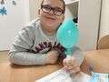 5. nadmuchany balon pod wpływem reakcji sody z octem chłopiec siedzi przy stole i trzyma balon