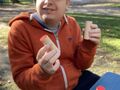 Chłopiec siedzi na ławce w rękach trzyma puszki szmerowe Montessori. Uczeń dobiera je parami tak aby szery były takie same 