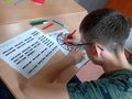 Uczeń siedzi przy ławce szkolnej wykonuje zadanie na karcie pracy 