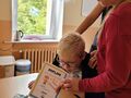 2. Dziewczynka wręcza koledze dyplom i słodki upominek
