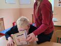 3. Dziewczynka wręcza koledze dyplom i słodki upominek