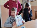 4. Chłopiec prezentuje dyplom który otrzymał od koleżanek. Jedna dziewczynka siedzi druga stoi 