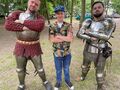 uczeń stoi z dwoma przebranymi rycerzami w zbroi