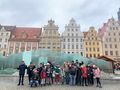 11. uczniowie na jarmarku razem z nauczycielami stoją przy fontannie