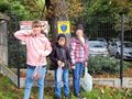 2. Dwie dziewczynki i chłopiec stoją trzymając worki z kasztanami. Obok idzie kot 