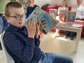 Uczeń siedzi na krześle i czyta wiersz 