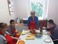 uczniowie siedzą przy stole i omawiają z wychowawcą etapy wykonania potrawy