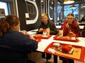 Dwie dziewczyny i jeden chłopak siedzą przy stole w restauracji McDonalds. Jedzą zamówione posiłki podane na tackach 