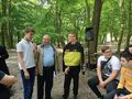 3.uczniowie stoją razem z ks.Rafałem i modlą się do mikrofonu z boku dwoje uczniów siedzi na ławce