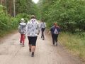 wychowankowie maszerują drogą leśną zdjęcie z tyłu